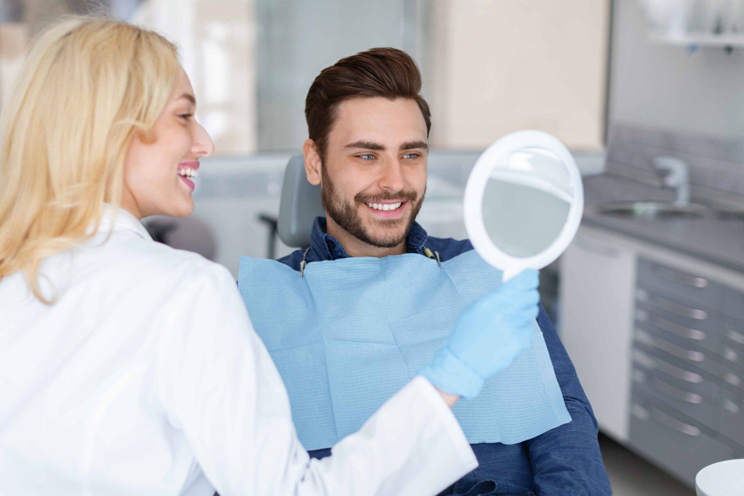 Dentist showing a patient their smile results with a hand mirror.