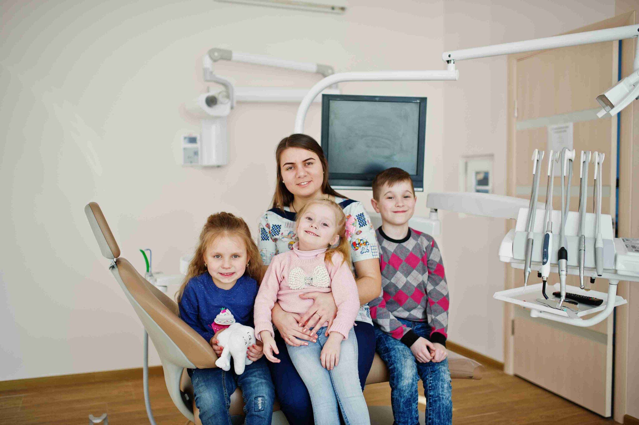 Family with three children sitting in a modern dental exam room.