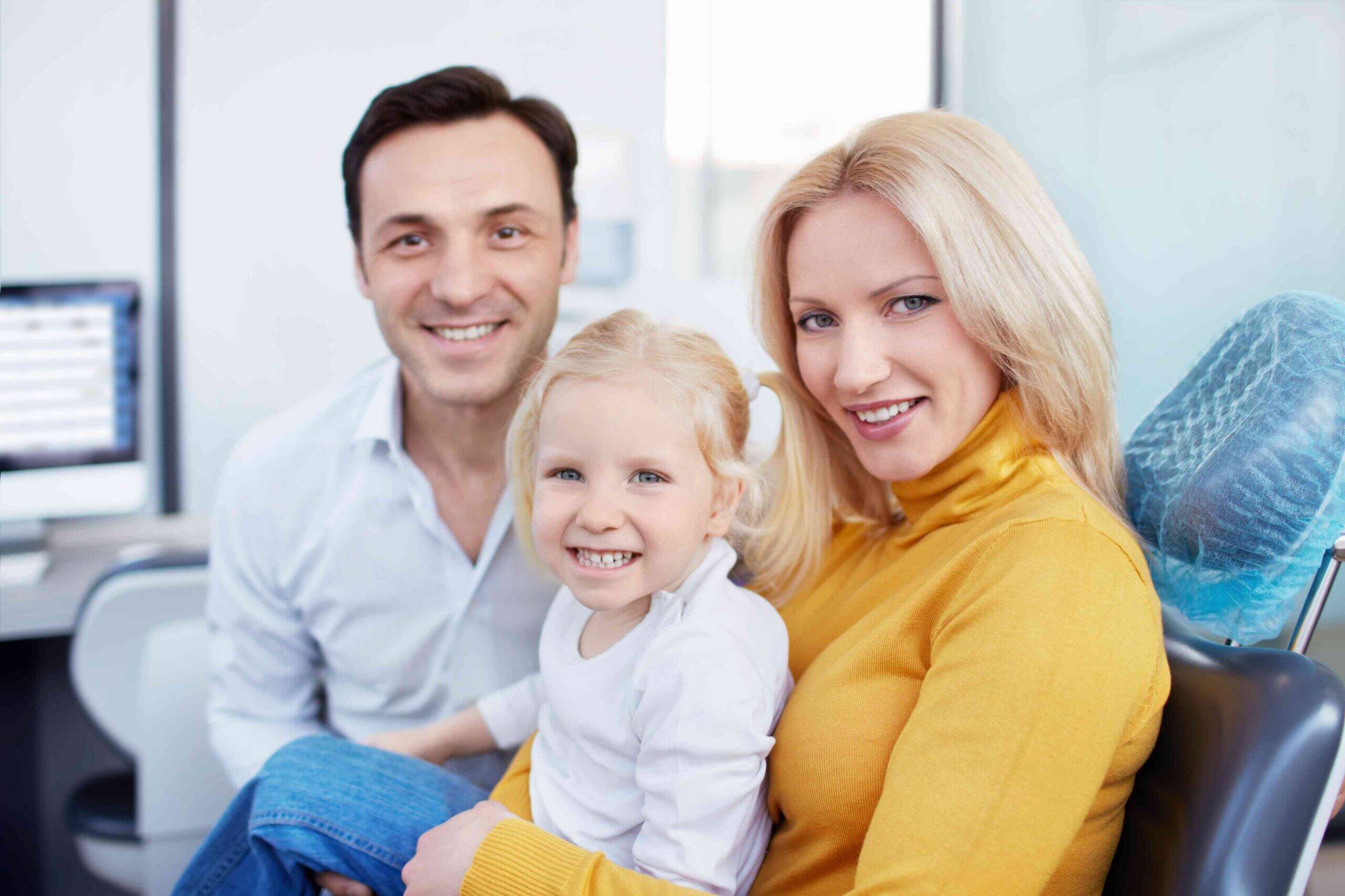 Smiling family sitting together in a dental office.