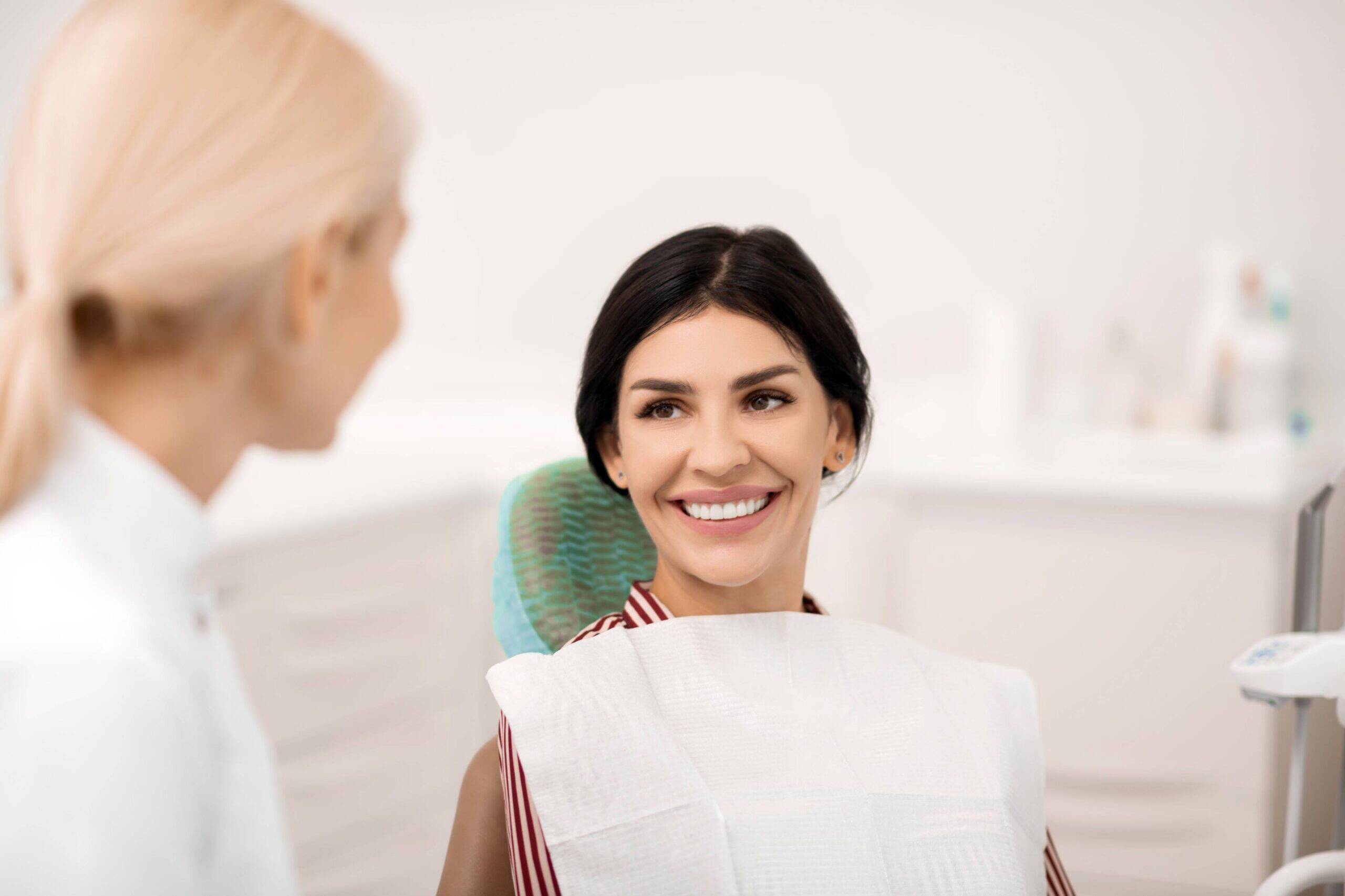 Smiling patient talking with dentist during consultation.